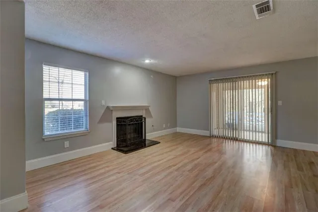 an empty room with wooden floor a fireplace and windows
