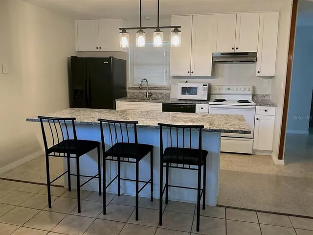 a kitchen with granite countertop a table chairs stove and cabinets