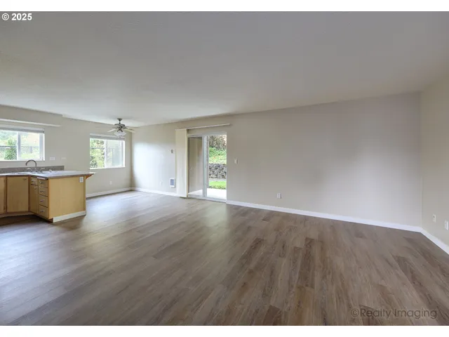 a view of an empty room with window and wooden floor