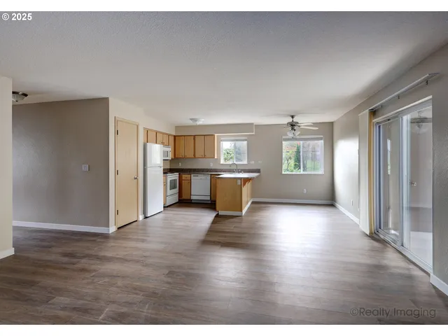 a view of a big room with wooden floor and windows