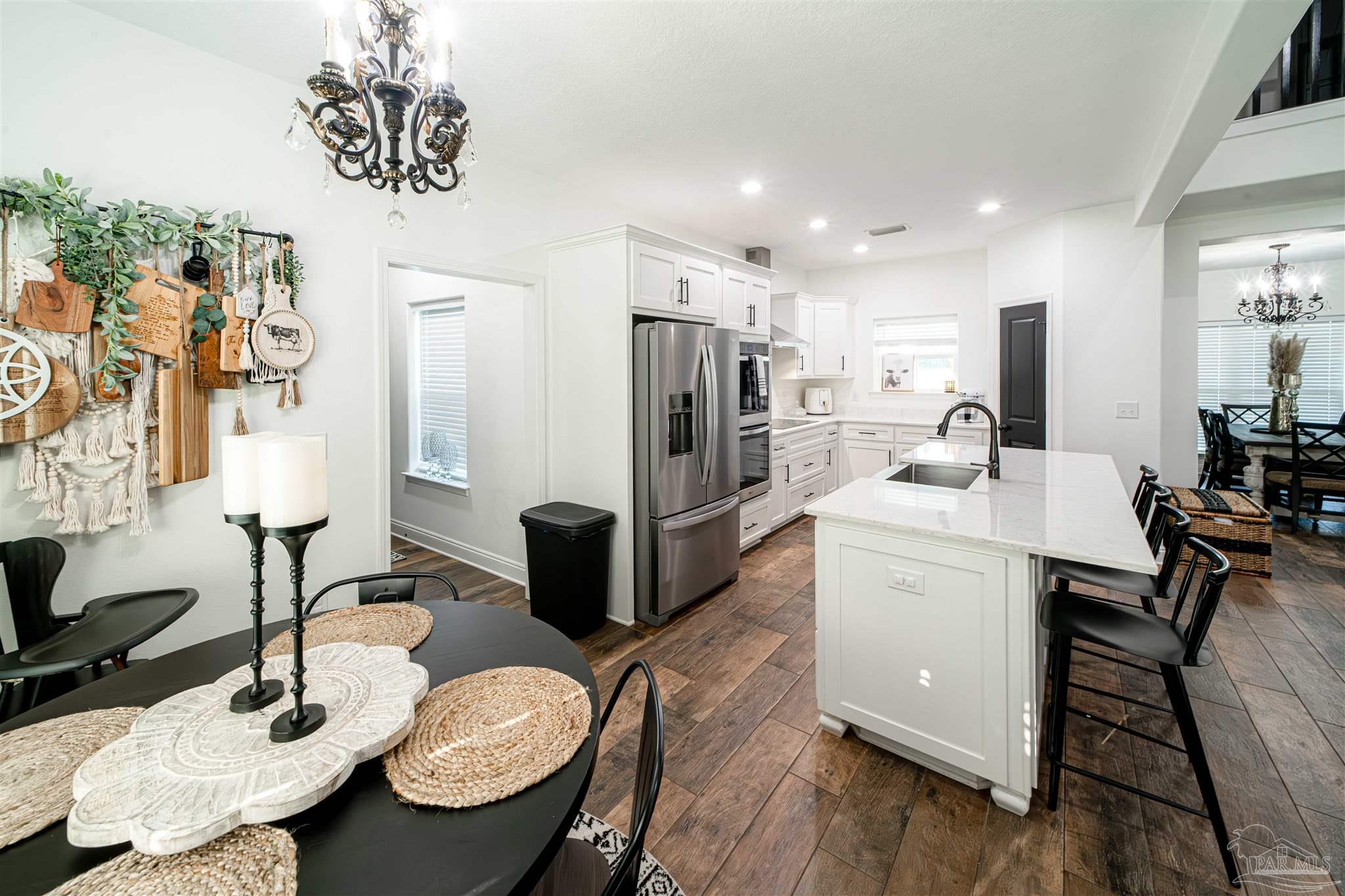 8165 Chumuckla Highway Pace, FL 32571 - Photo 18 of 50 a kitchen with sink refrigerator dining table and chairs