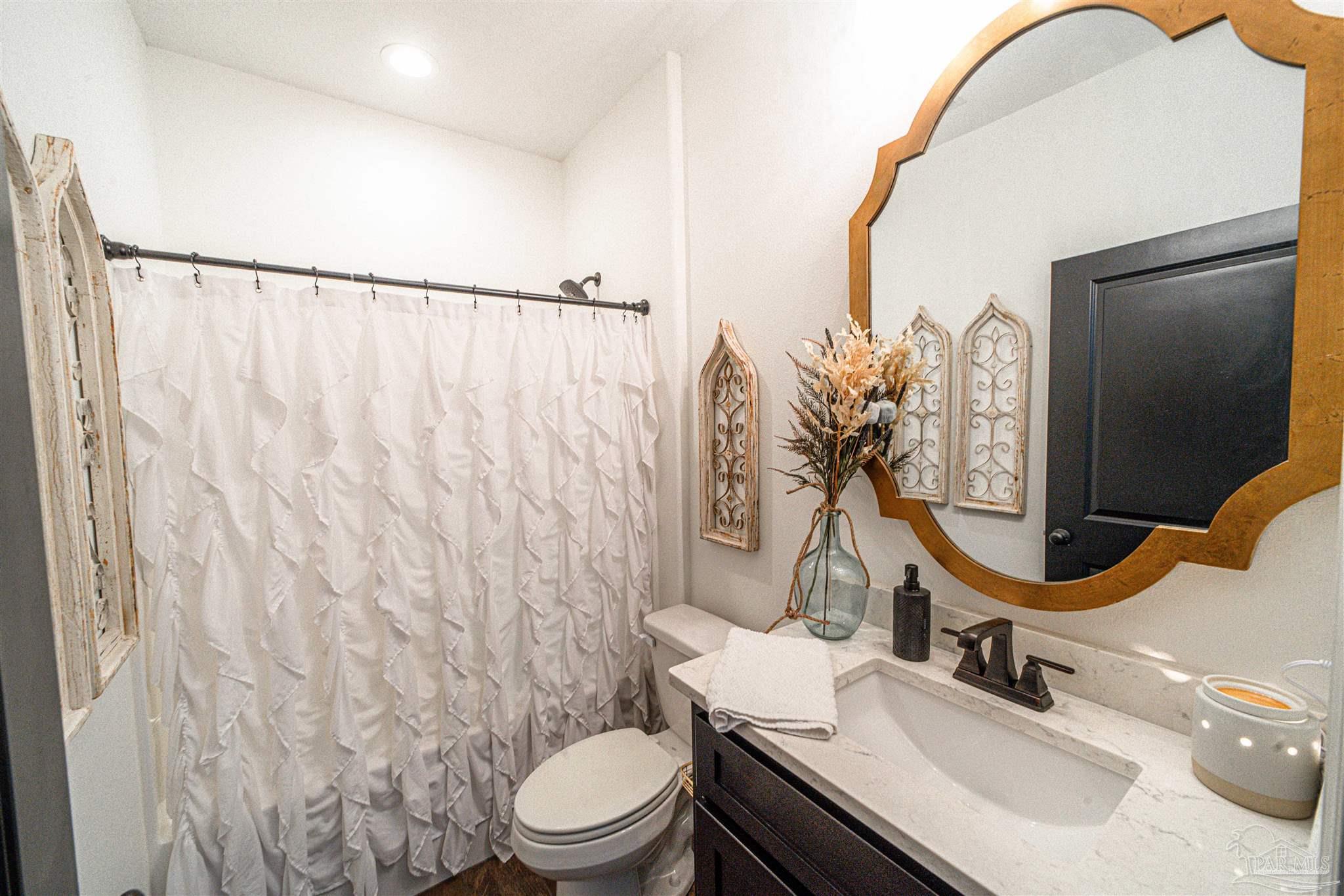 8165 Chumuckla Highway Pace, FL 32571 - Photo 30 of 50 a bathroom with a sink vanity mirror and toilet