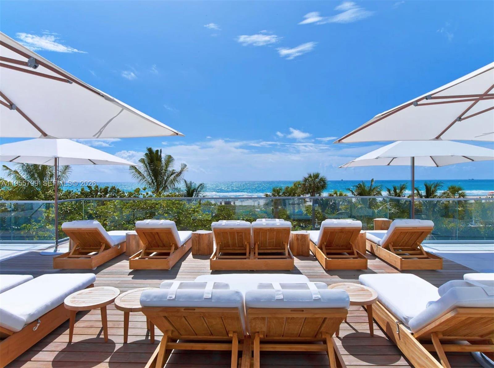102 24th Street, Unit 1427 Miami Beach, FL 33139 - Photo 72 of 77 a view of a patio with lawn chairs under an umbrella
