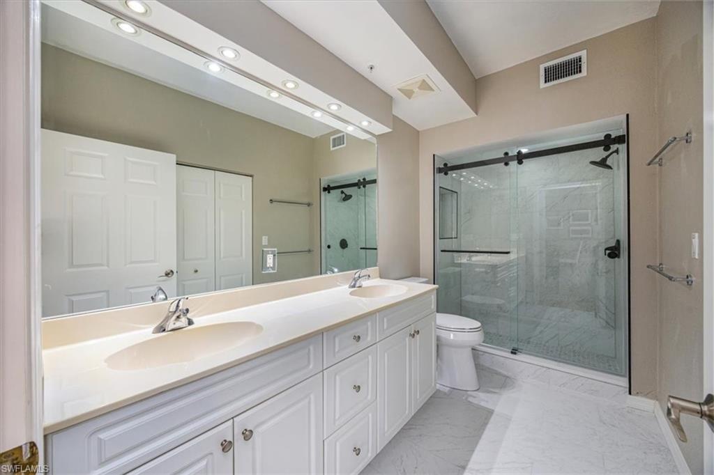 401 Bayfront Place, Unit 3404 Naples, FL 34102 - Photo 9 of 14 a bathroom with a double vanity sink toilet mirror and shower