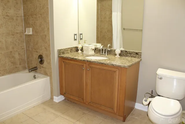 a bathroom with a granite countertop sink a toilet and bathtub
