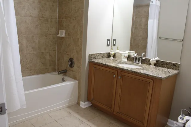 a bathroom with a granite countertop sink a mirror a bathtub and shower