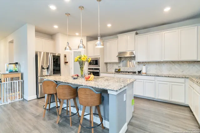 a kitchen with stainless steel appliances granite countertop a table chairs sink refrigerator and cabinets