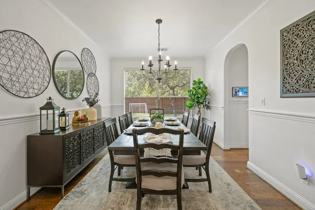 a dining room with furniture a rug a potted plant and a chandelier