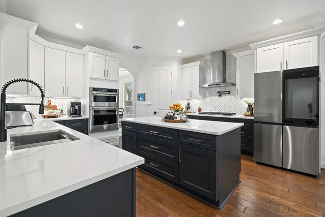 a kitchen with stainless steel appliances a sink a stove a refrigerator and cabinets