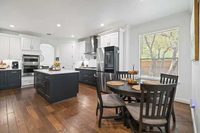 a room with stainless steel appliances kitchen island granite countertop a table chairs sink and cabinets