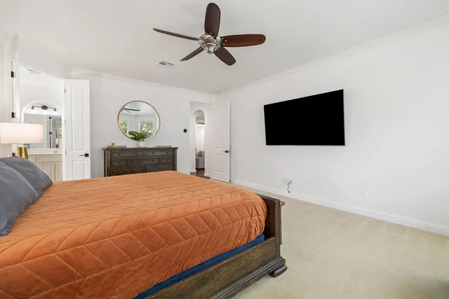 a bedroom with a bed a flat tv screen and a chandelier