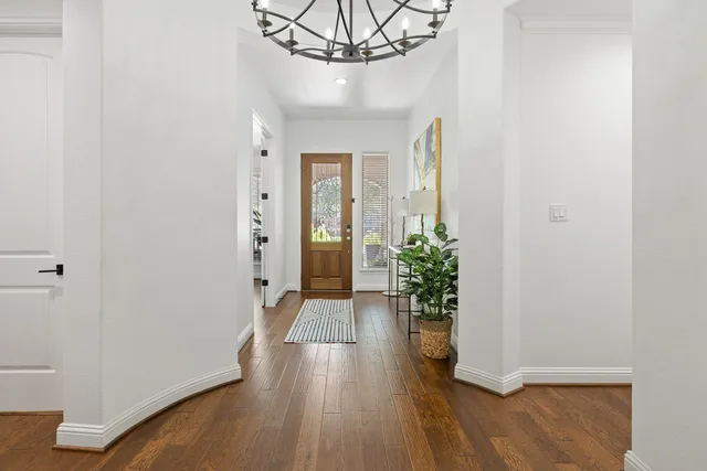a view of a hallway with wooden floor and a chandelier