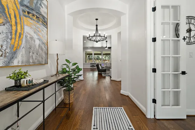 a hallway with wooden floor and chandelier