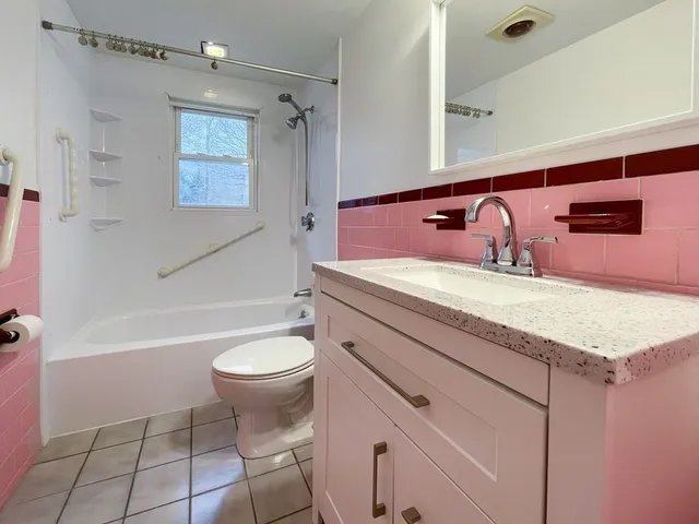 a bathroom with a granite countertop sink a toilet a mirror and bathtub