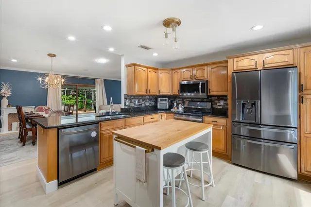 a kitchen with stainless steel appliances granite countertop a sink a stove and a refrigerator