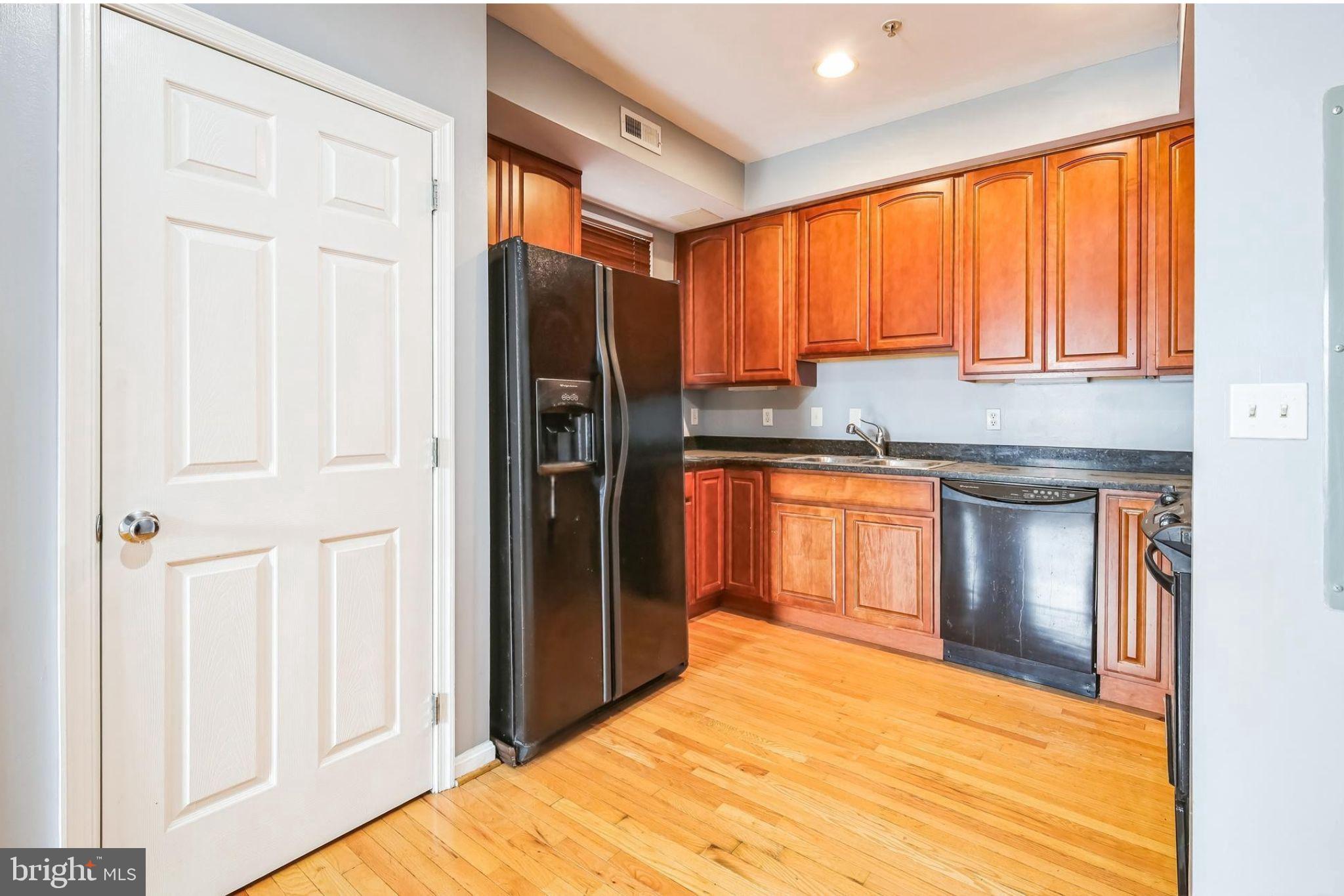 610 Irving Street Northwest, Unit 105 Washington, DC 20010 - Photo 16 of 28 a kitchen with stainless steel appliances granite countertop a refrigerator a sink dishwasher and wooden cabinets with wooden floor