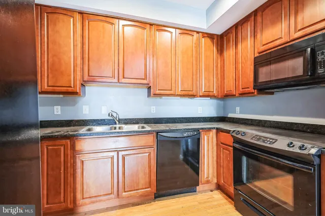 a kitchen with granite countertop wooden cabinets stainless steel appliances and a sink