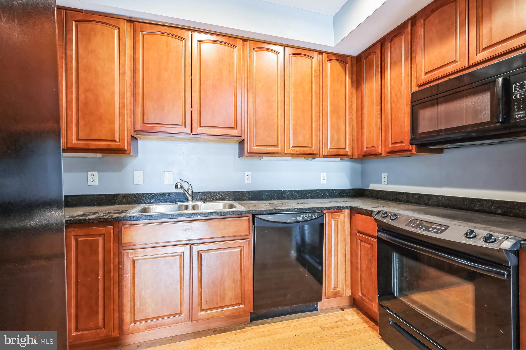 610 Irving Street Northwest, Unit 105 Washington, DC 20010 - Photo 18 of 28 a kitchen with granite countertop wooden cabinets stainless steel appliances and a sink