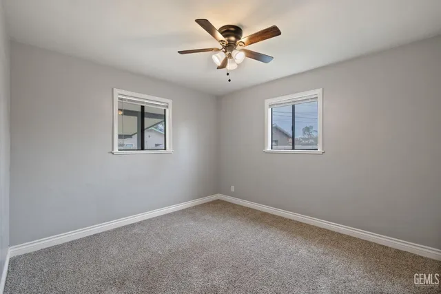 an empty room with a window and a ceiling fan