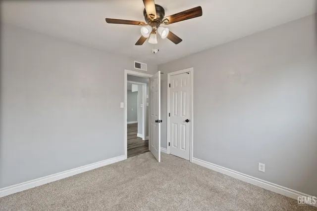 a view of a livingroom with a ceiling fan & windows