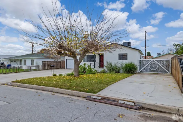 a view of a white house next to a road with big trees