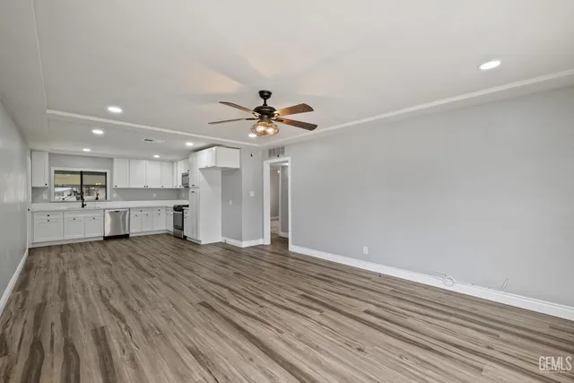 a view of an empty room with wooden floor and a ceiling fan