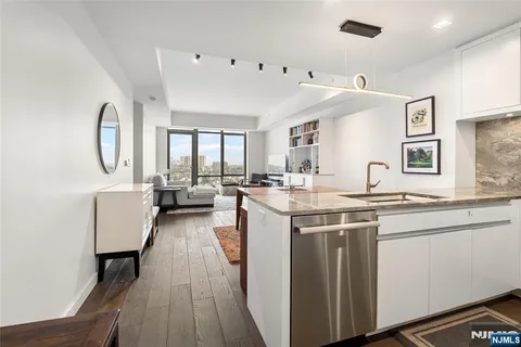 a living room with stainless steel appliances kitchen island granite countertop a sink and wooden floor