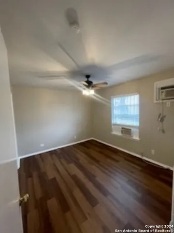 an empty room with wooden floor fan and windows