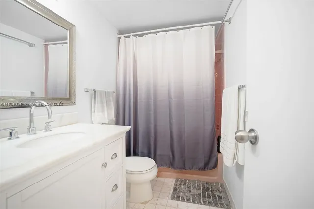 a bathroom with a sink a toilet a shower curtain and a large mirror