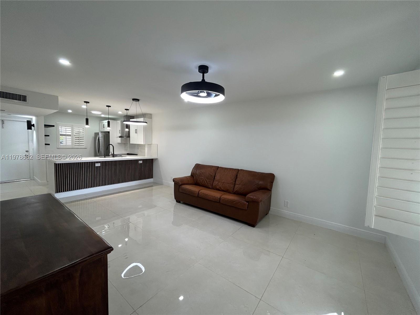 300 Berkley Road, Unit 108 Hollywood, FL 33024 - Photo 14 of 41 a living room with kitchen island stainless steel appliances furniture a rug and a counter top