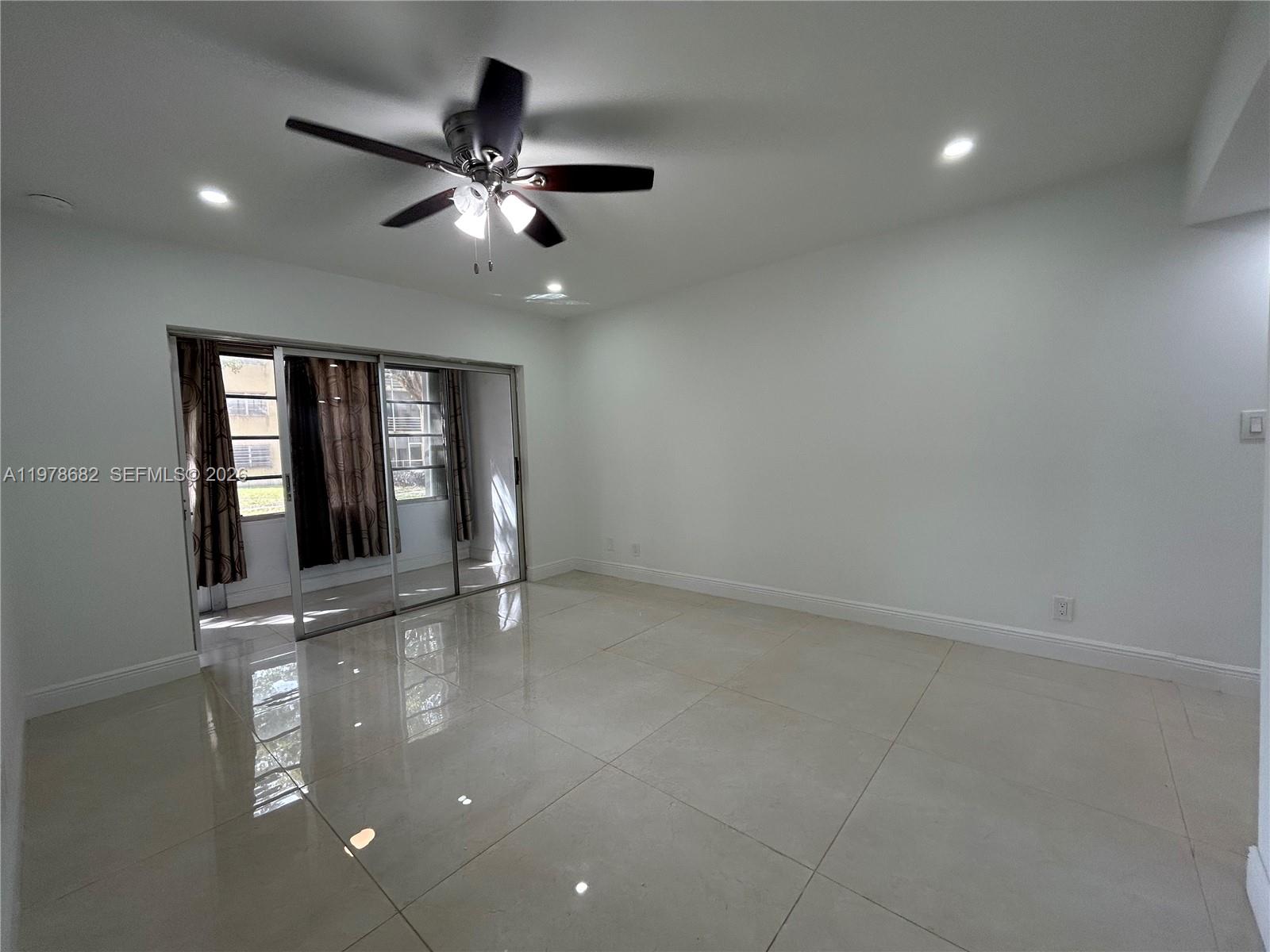 300 Berkley Road, Unit 108 Hollywood, FL 33024 - Photo 18 of 41 an empty room with chandelier fan and windows