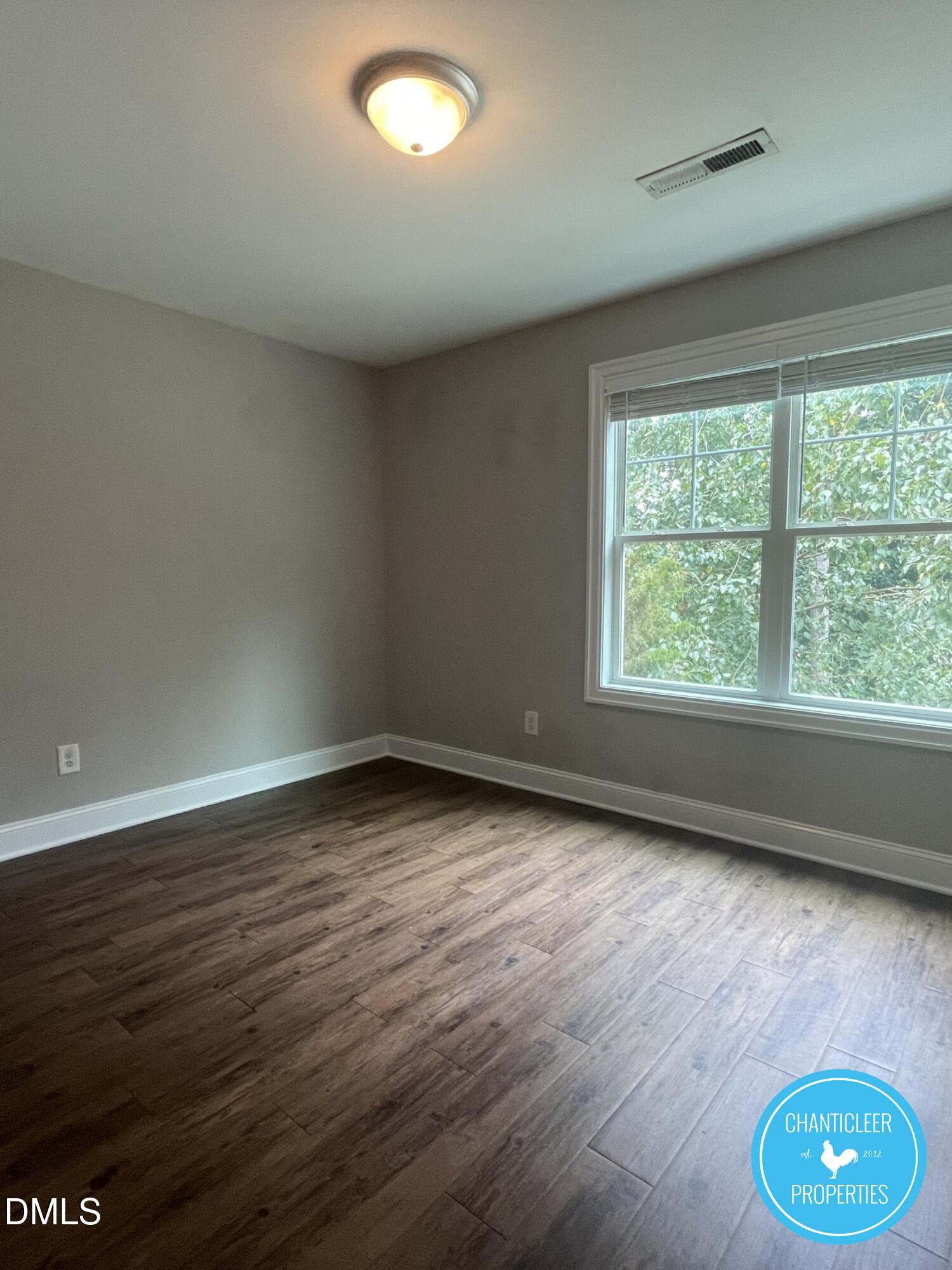 911 Chaney Road, Unit 100 Raleigh, NC 27606 - Photo 8 of 19 wooden floor in an empty room with a window