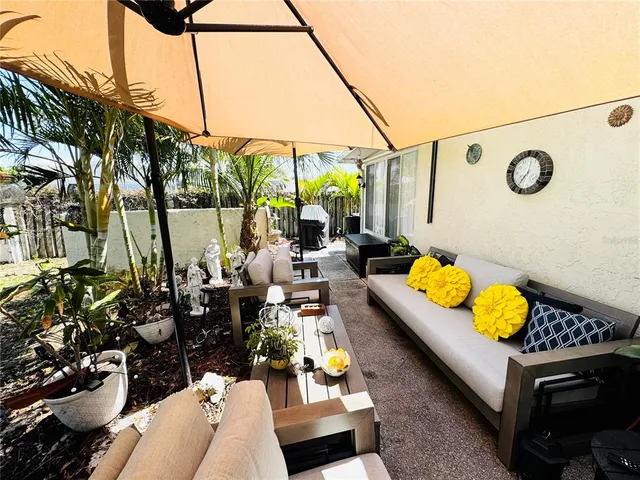 a view of a patio with couches table and chairs under an umbrella with a barbeque