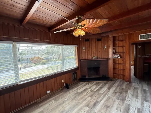 an empty room with a fireplace cabinet and windows