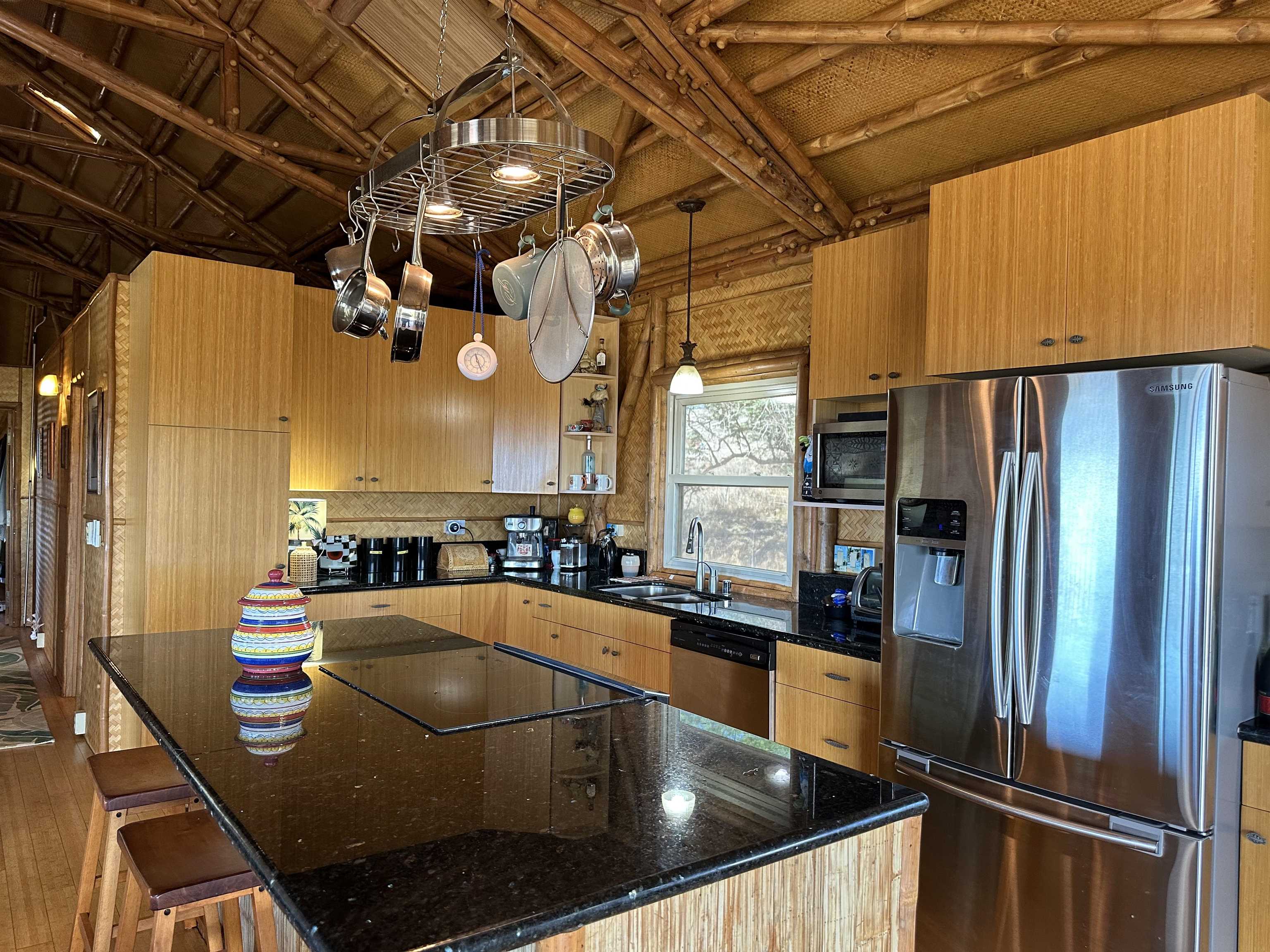 206 Awawa Road Maunaloa, HI 96770 - Photo 13 of 28 a kitchen with stainless steel appliances kitchen island granite countertop a table chairs and a refrigerator