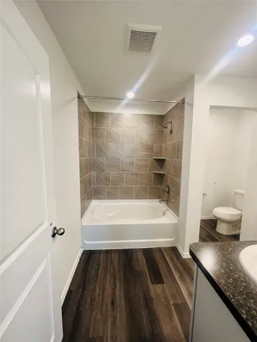 a bathroom with a granite countertop sink a toilet and bathtub