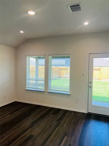 a view of an empty room with wooden floor and a window