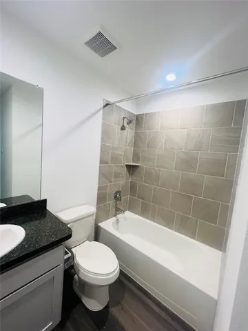 a bathroom with a granite countertop bathtub shower sink mirror vanity and toilet