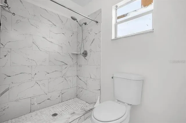 a white toilet sitting next to a shower