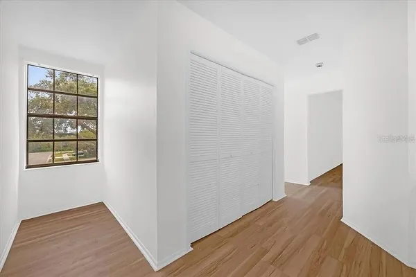 a view of an empty room with wooden floor and a window