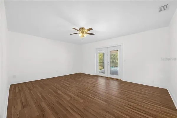 a view of an empty room with window and wooden floor