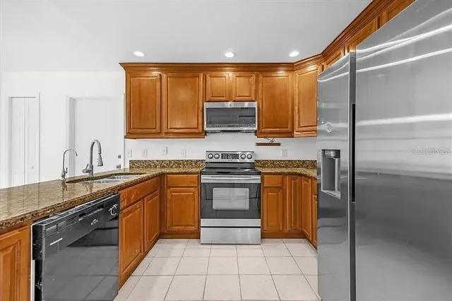 a kitchen with stainless steel appliances granite countertop a stove a sink and a refrigerator