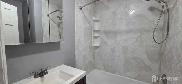 a bathroom with a white bath tub a shower and a sink
