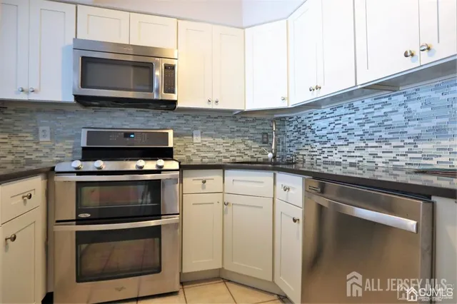 a kitchen with granite countertop white cabinets stainless steel appliances and a counter space