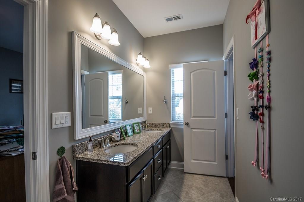 8037 Clems Branch Road, Unit 137 Indian Land, SC 29707 - Photo 20 of 24 a bathroom with a granite countertop sink a light fixture and a mirror