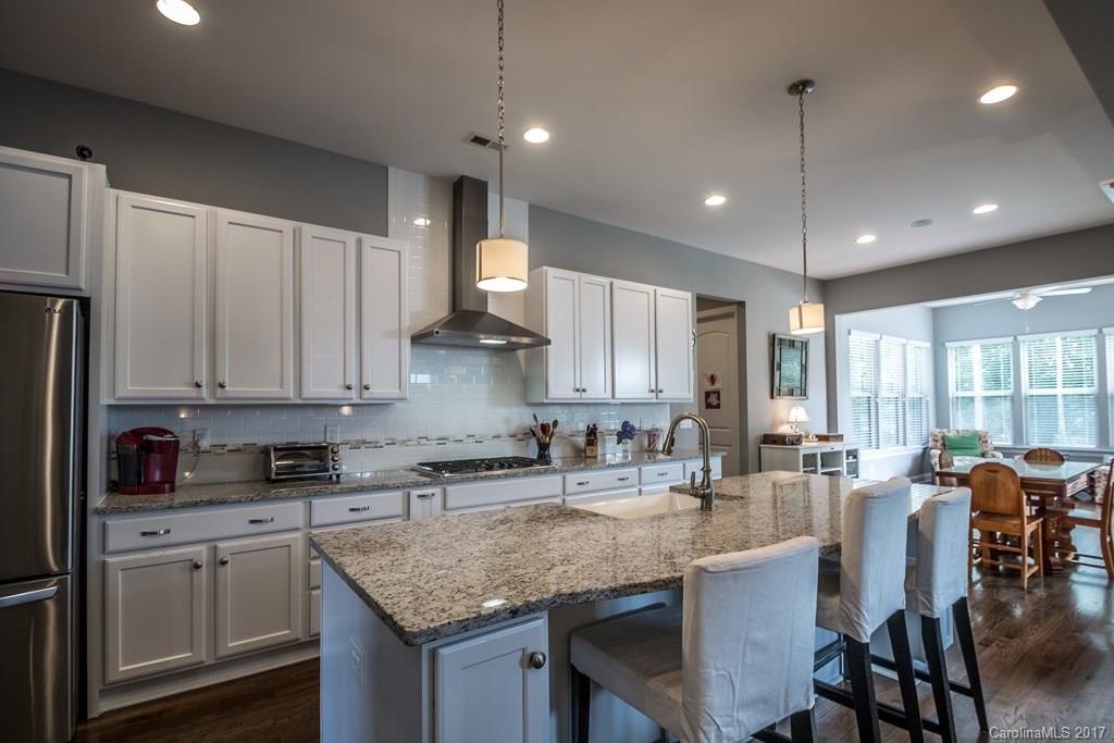 8037 Clems Branch Road, Unit 137 Indian Land, SC 29707 - Photo 4 of 24 a kitchen with kitchen island granite countertop a table chairs sink and cabinets