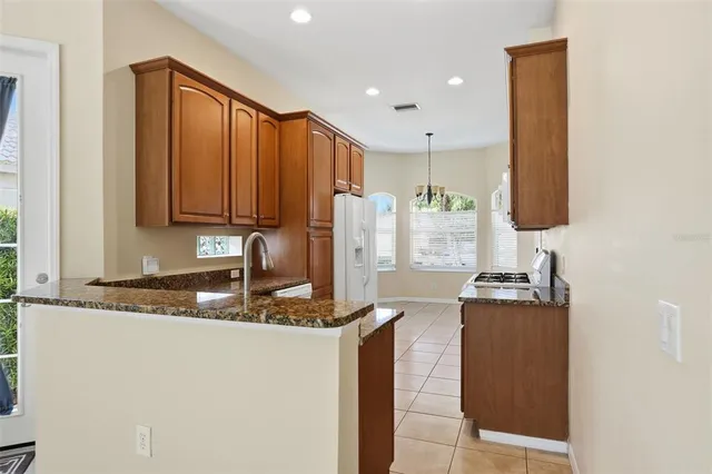 a kitchen with stainless steel appliances granite countertop a refrigerator a stove and a sink