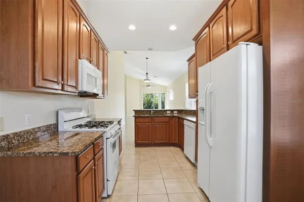a kitchen with stainless steel appliances granite countertop a refrigerator a stove and a sink