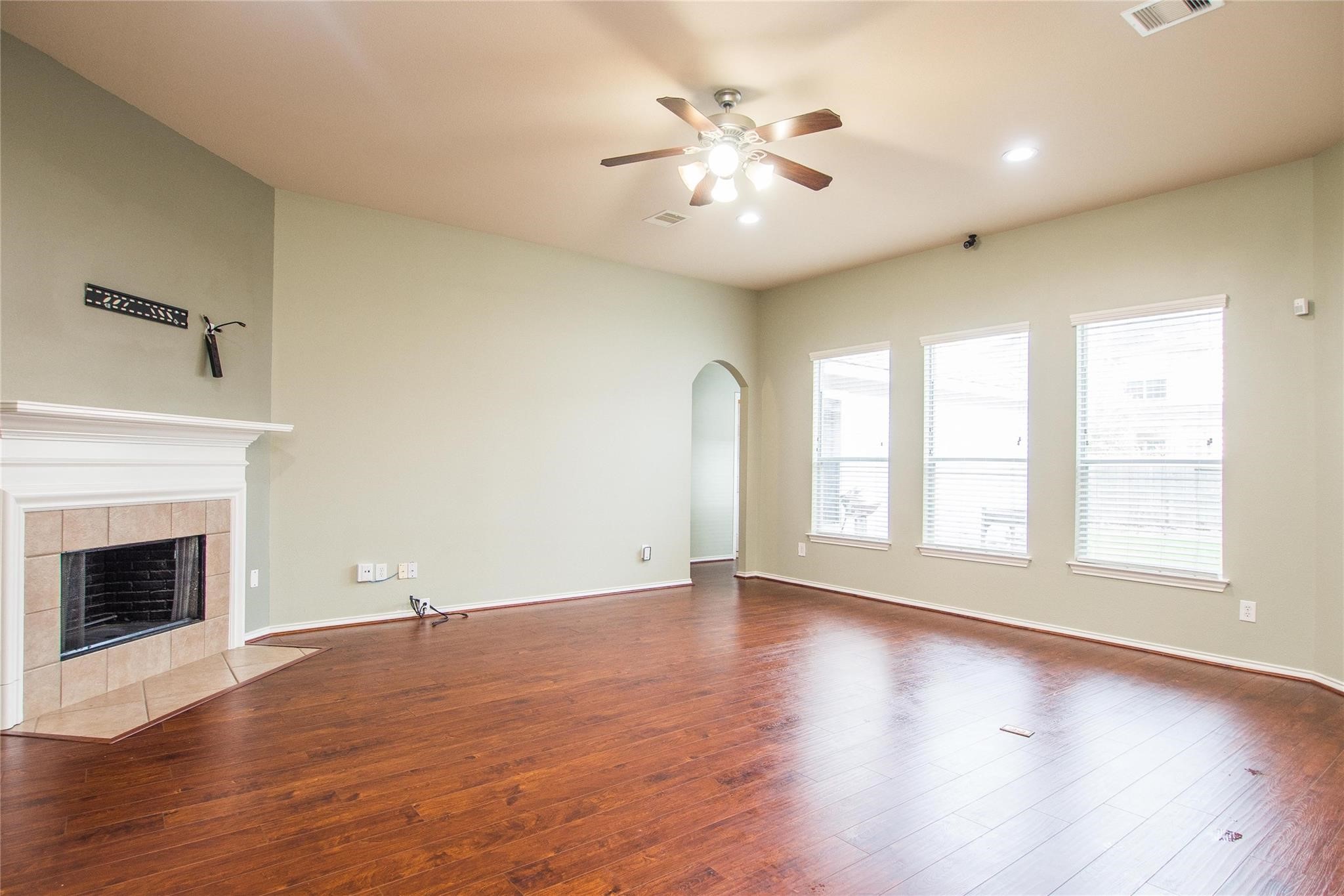 8847 Distant Woods Drive Houston, TX 77095 - Photo 8 of 26 an empty room with wooden floor fireplace and windows