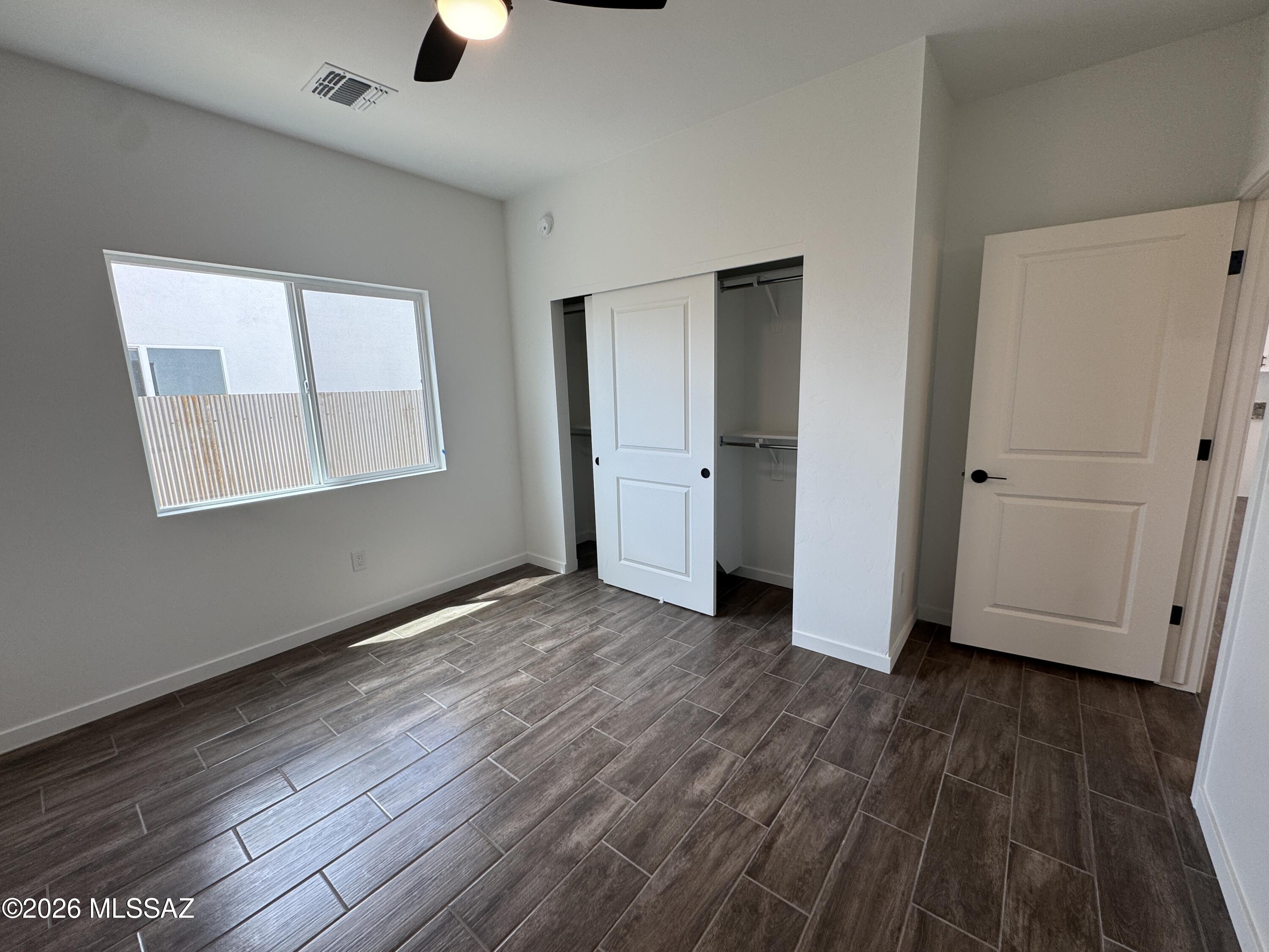 2130 North Ralph Avenue, Unit 1 Tucson, AZ 85712 - Photo 5 of 11 an empty room with wooden floor closet and windows